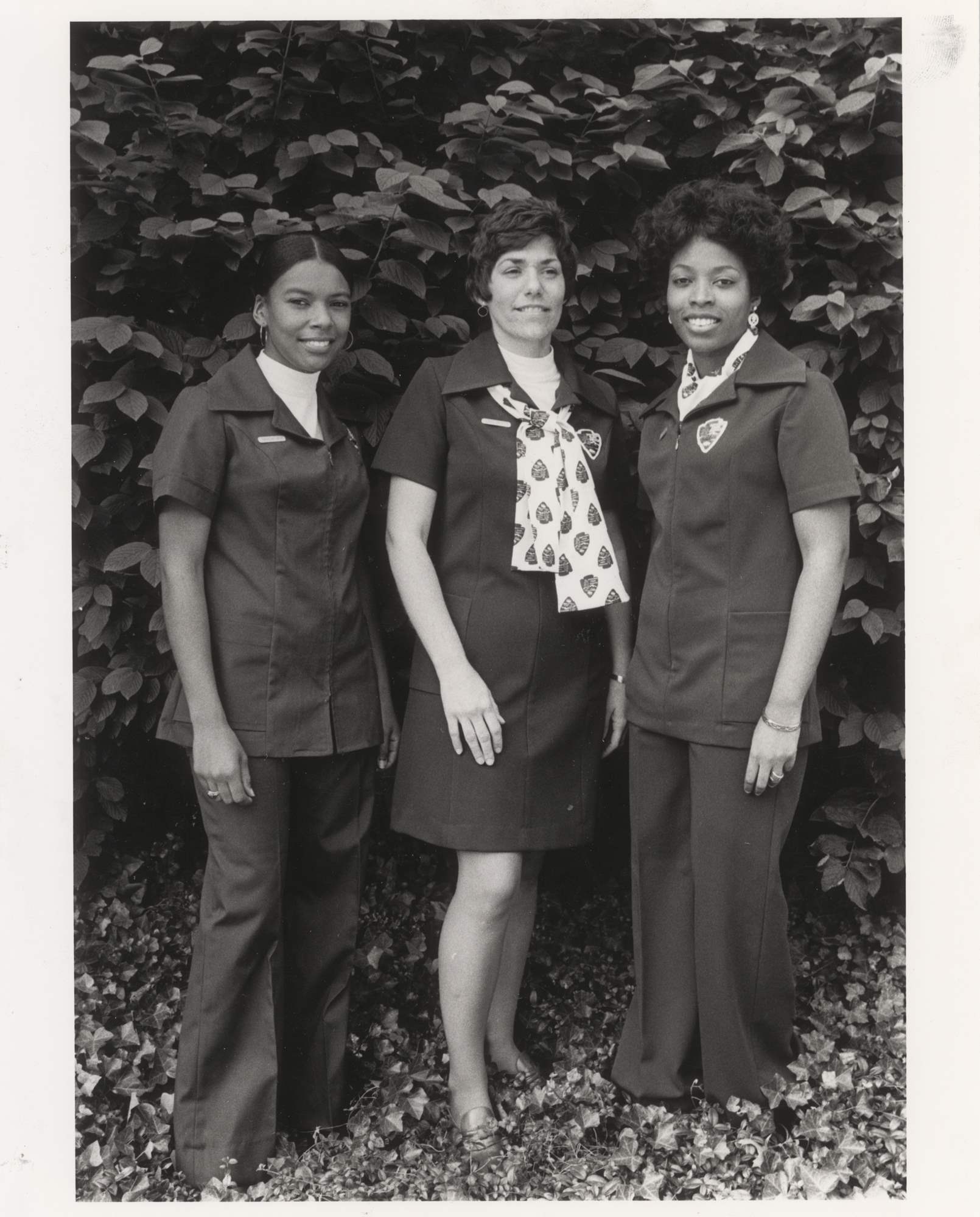 Three women pose in NPS uniforms. Two wear pantsuits and one a dress. The uniforms have arrowhead patches instead of ranger badges.